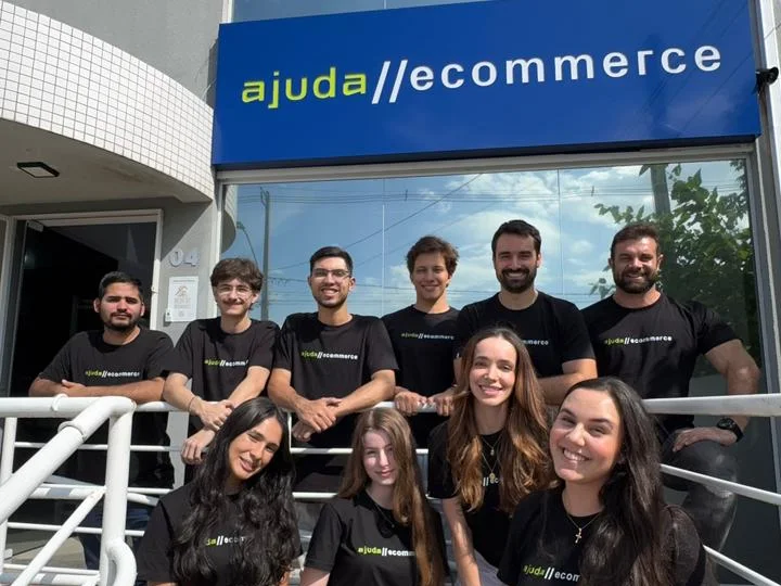 O time da Ajuda Ecommerce em frente à fachada do escritório, com o letreiro ajuda//ecommerce